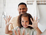 Happy mixed race father and daughter washing their hands  together in a bathroom at home. Single African American parent teaching his daughter about hygiene while having fun and being playful