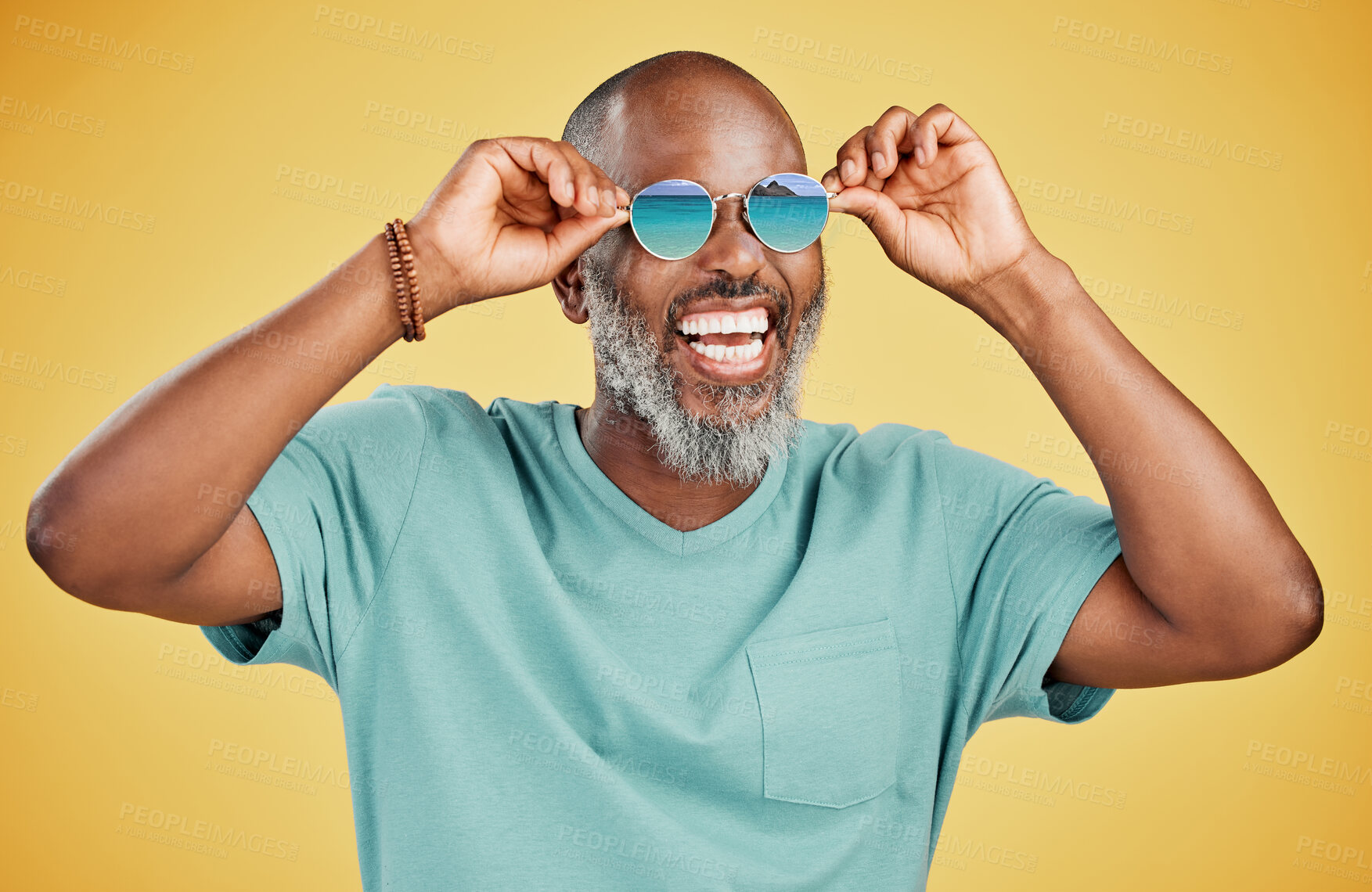 Buy stock photo Happy mature African American man standing alone against yellow background in a studio and posing with sunglasses. Smiling black man feeling fashionable and cool while wearing glasses. Summer and beach