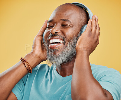 One mature african american man listening to music using wireless headphones. Happy man with a grey beard smiling while enjoying music. Eyes closed, getting lost in the music and feeling carefree