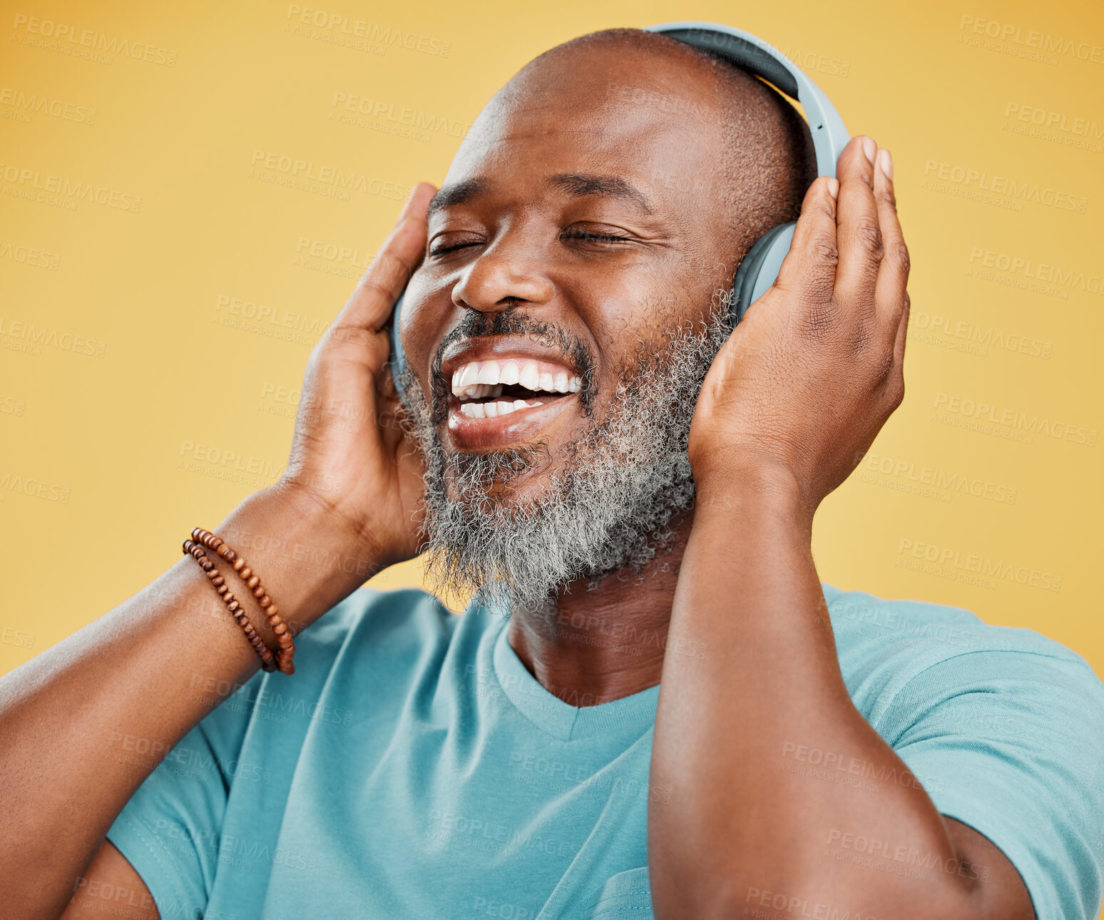 Buy stock photo One mature african american man listening to music using wireless headphones. Happy man with a grey beard smiling while enjoying music. Eyes closed, getting lost in the music and feeling carefree