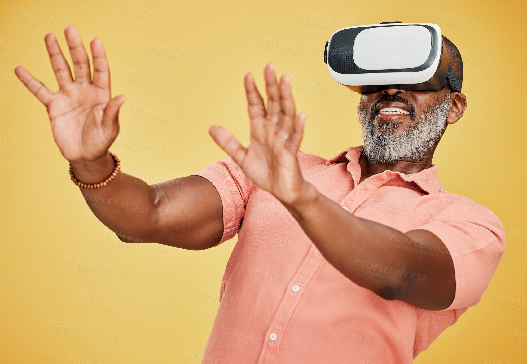 Buy stock photo One mature african american man using a virtual reality headset while standing in studio isolated against a yellow background. Handsome man with a grey beard using wireless technology to play games