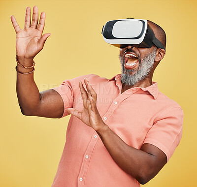 One mature african american man using a virtual reality headset while standing in studio isolated against a yellow background. Handsome man with a grey beard using wireless technology to play games