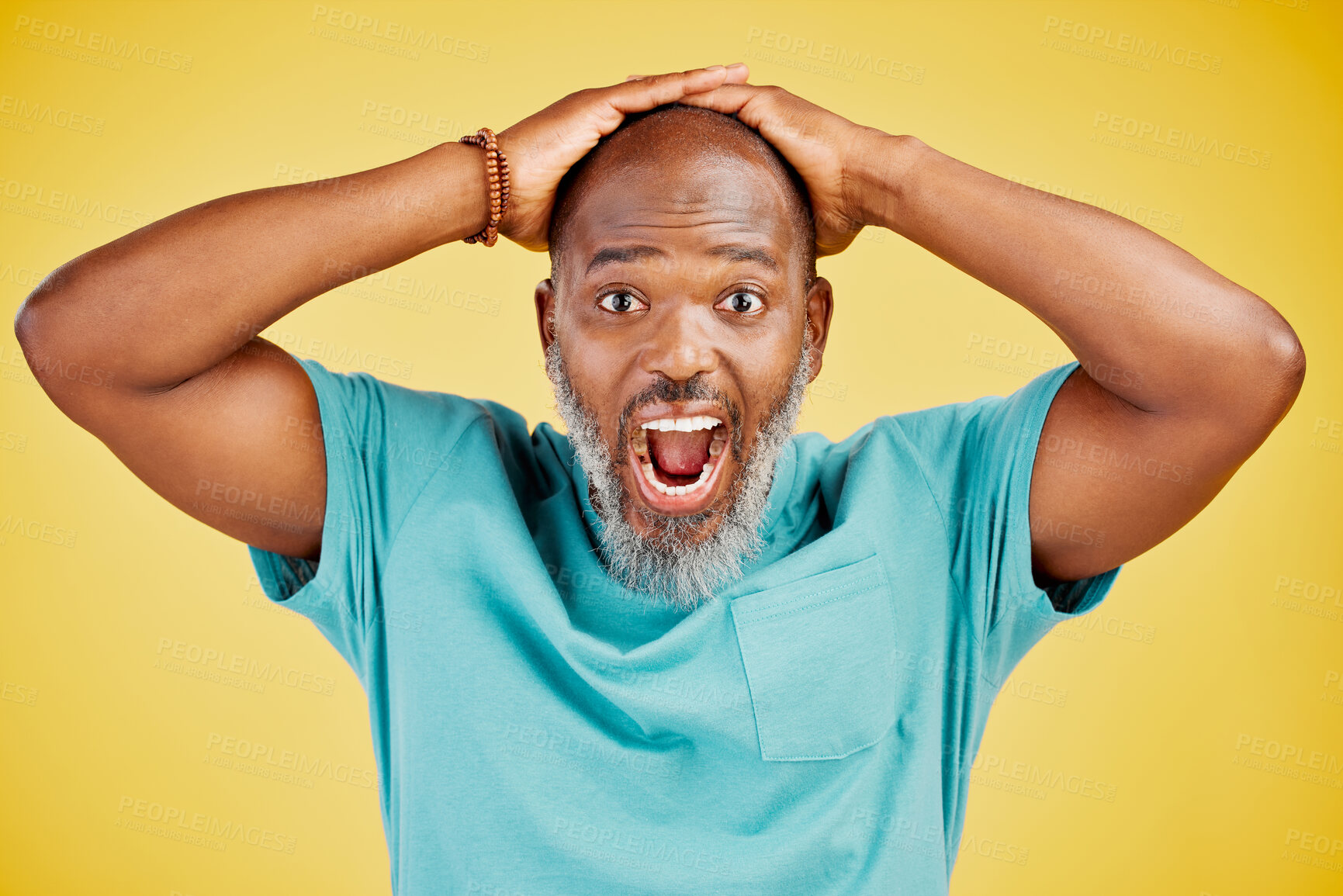 Buy stock photo Mature African american man with grey beard standing with his hands on his head and looking shocked or surprised. Man with astonished facial expression while standing against yellow studio background