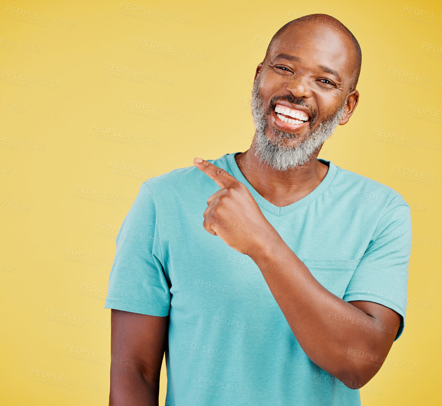 Buy stock photo Mature african man laughing and pointing in a direction against a yellow studio background. Black guy giggling and making a pointing gesture reacting with laughter while looking cheerful and happy. Lighten the mood with an amusing and funny joke