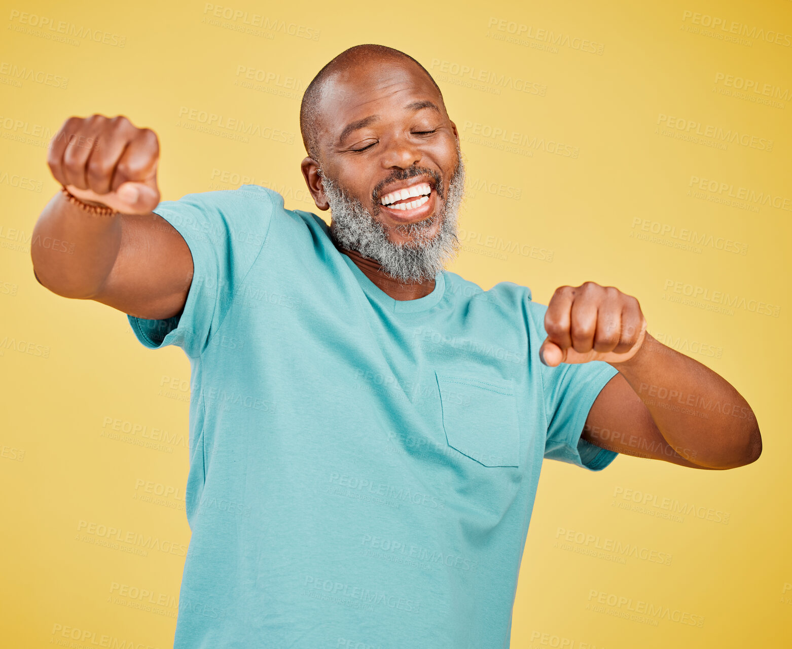 Buy stock photo A mature african man looking ecstatic while while celebrating and dancing by making a fist pump gesture with his hands and singing against a yellow studio background. Dance like nobody's watching
