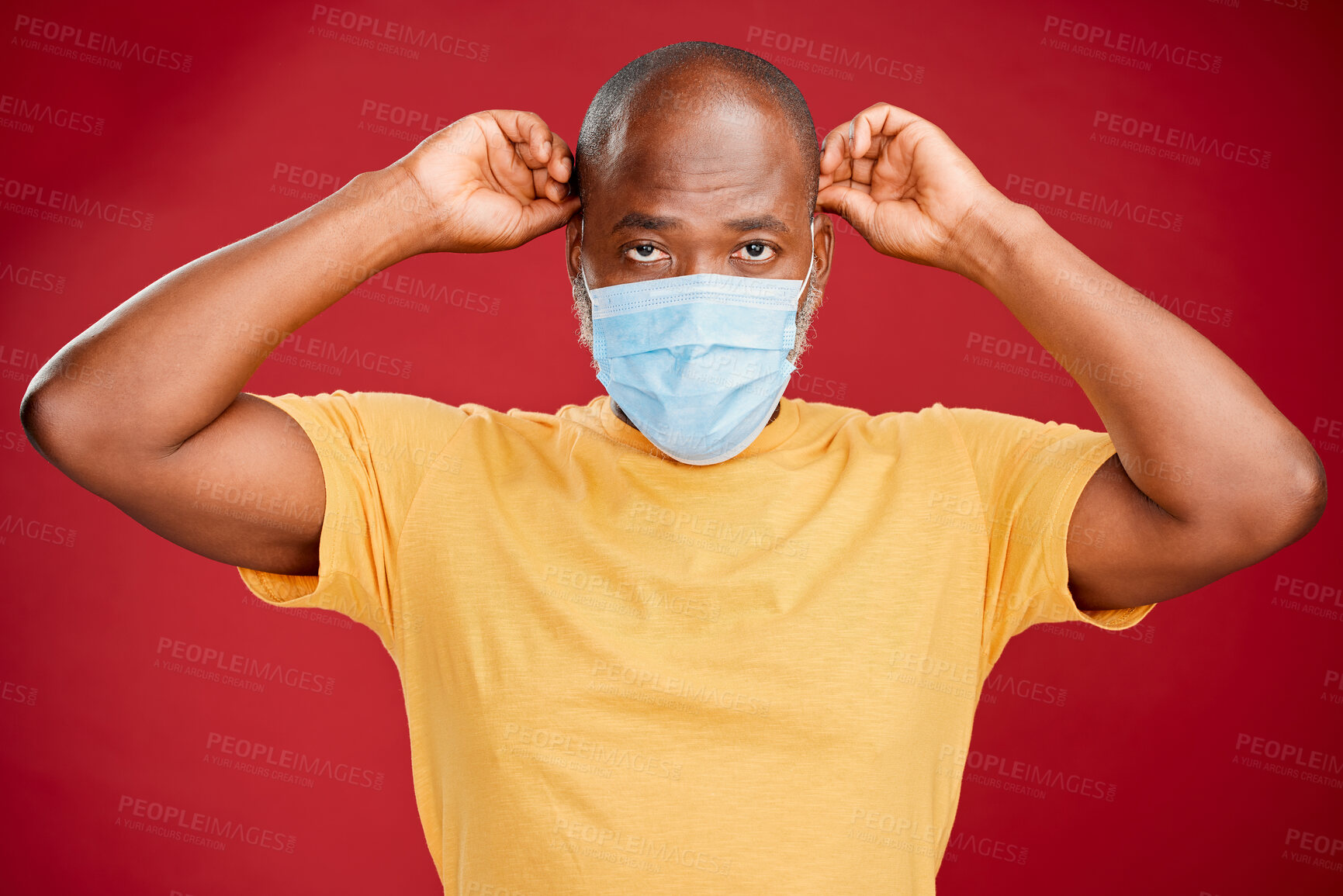 Buy stock photo Young african american man wearing a mask standing against a red studio background. Health, healthcare, safety. Sick, disease, risk. covid, outbreak, virus