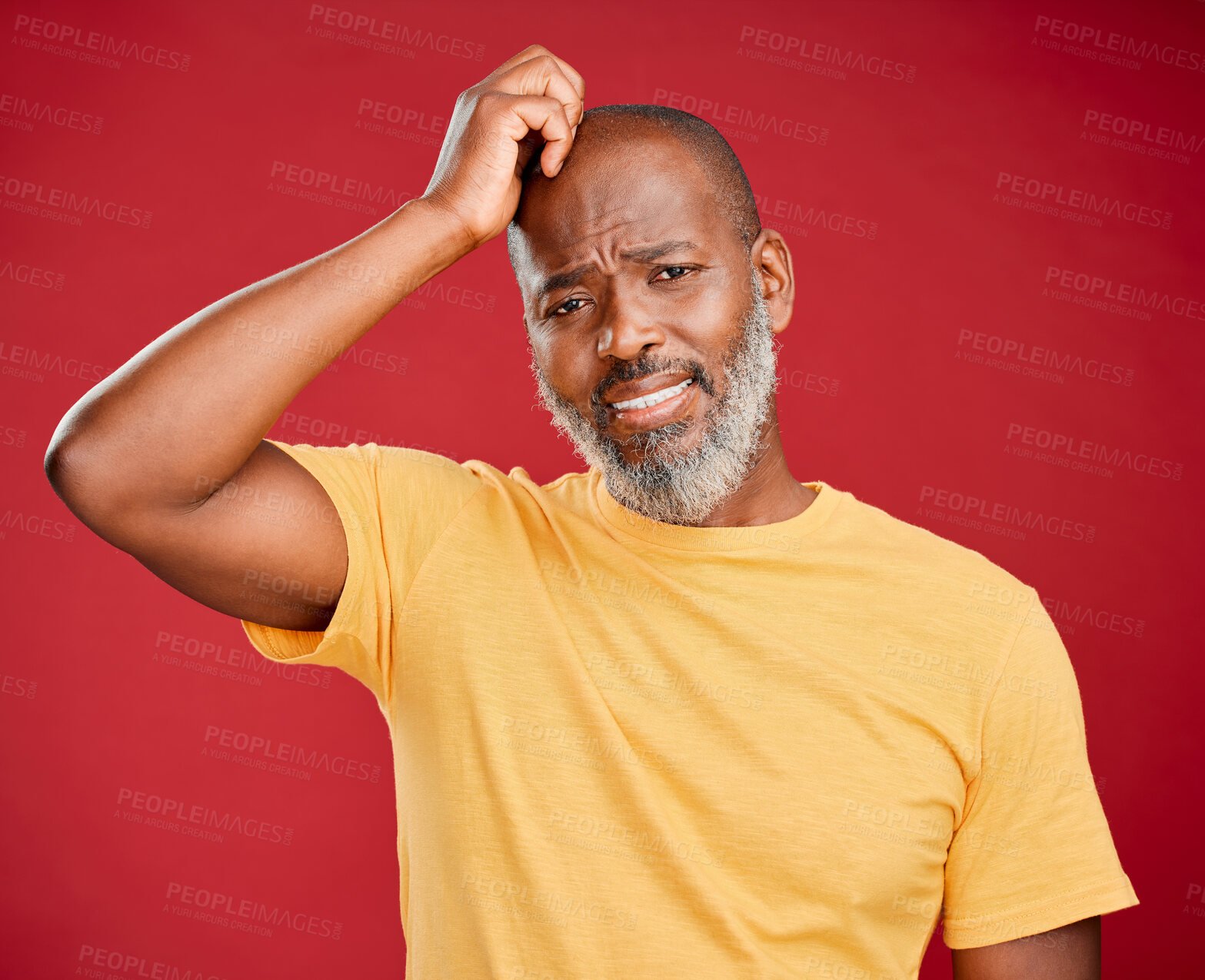 Buy stock photo Mature african american man with a beard scratching his head standing against a red studio background. Unhappy, frowning, unsure. Anxiety, sad, worried
