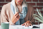 Mature woman reading financial insurance documents at home.A senior woman reading financial paperwork planning her retirement. A mature woman holding her glasses reading legal paperwork