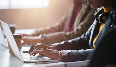 Buy stock photo A focused businesswoman typing on her laptop while sitting next to her coworker. Closeup of an african american businesswoman working on her laptop in an office with her colleague