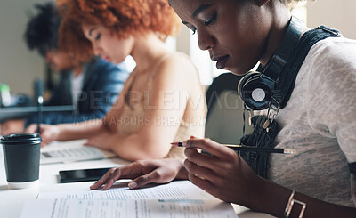 Buy stock photo A diverse group of students reading paperwork and studying. A young student reading her academic texts before making notes. A serious academic student reading through her reports while studying