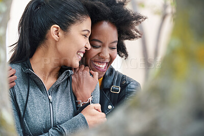 Buy stock photo Two cheerful friends hugging one another and laughing during a trip to the park. A happy young woman affectionately hugging her friend. Two friends smiling and hugging outside in the park