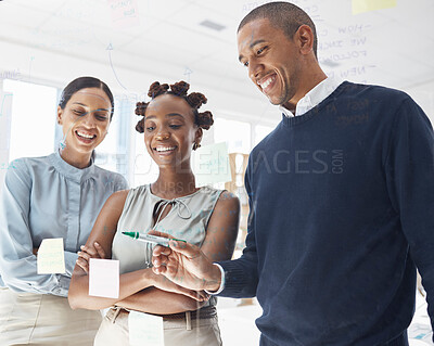 Three happy diverse businesspeople writing ideas and brainstorming together in an office at work. Cheerful hispanic businessman making a note on a glass window with female colleagues
