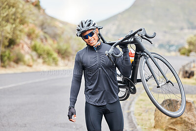 A young mixed race male cyclist carrying his bicycle after taking a ride outdoors while his helmet and sunglasses. Young hispanic male looking happy after a bike ride on a mountain pass. Physical fitness is the most important key to a healthy body