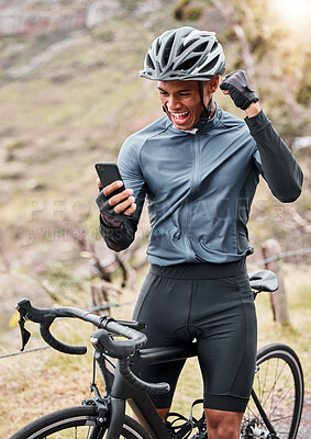 Buy stock photo African American cyclist wearing a helmet while using a cellphone and celebrating a win. Male expressing joy while cycling on a bicycle and exercising outside. Success at tracking his speed on an app