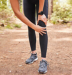 Close up of an athletic young woman holding her knee in pain while exercising outdoors. Active woman wearing running shoes and suffering an unfortunate joint injury while out for a workout in nature