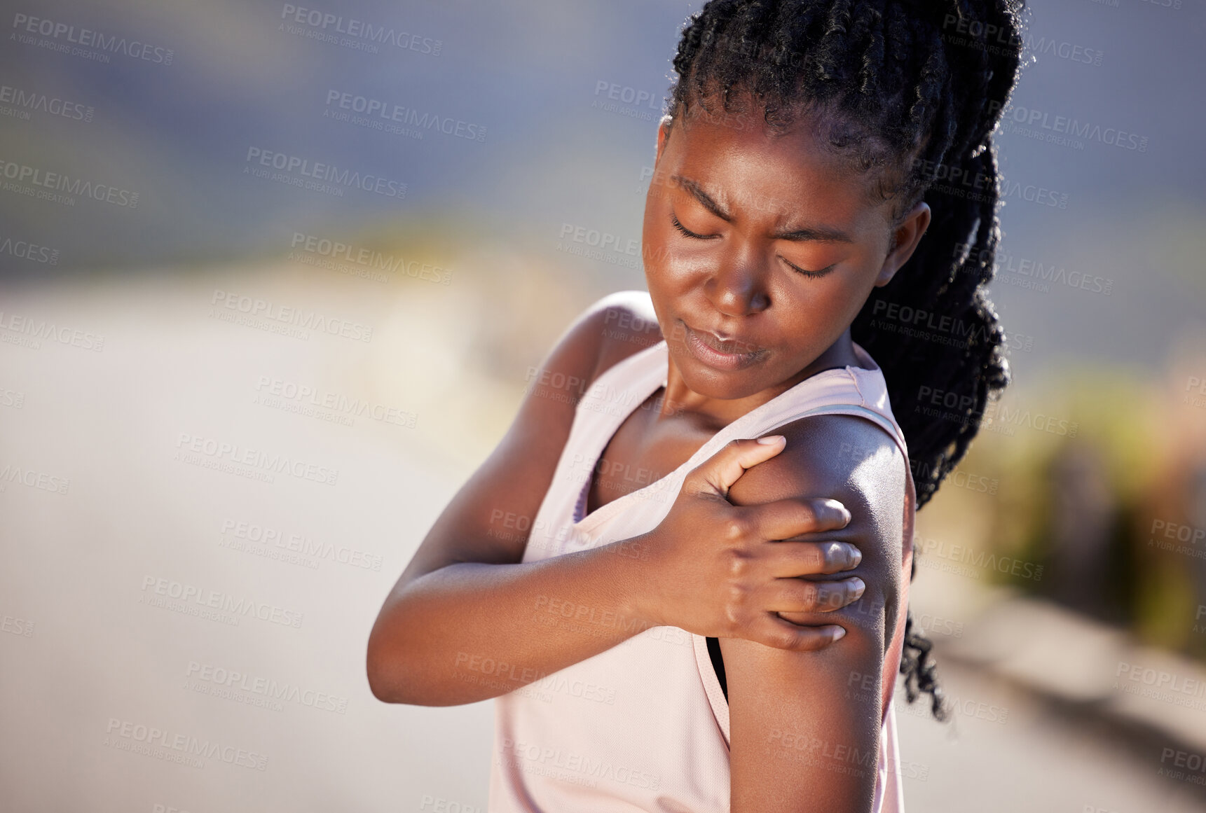 Buy stock photo Active young black woman holding her shoulder in pain while exercising outdoors. Athlete suffering with a sore arm injury, causing discomfort and strain. Bone and muscle sprain from a fractured joint