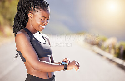 One beautiful african american female athlete checking her smartwatch while exercising outdoors. A young athletic woman smiling while tracking her progress on a fitness watch during her workout