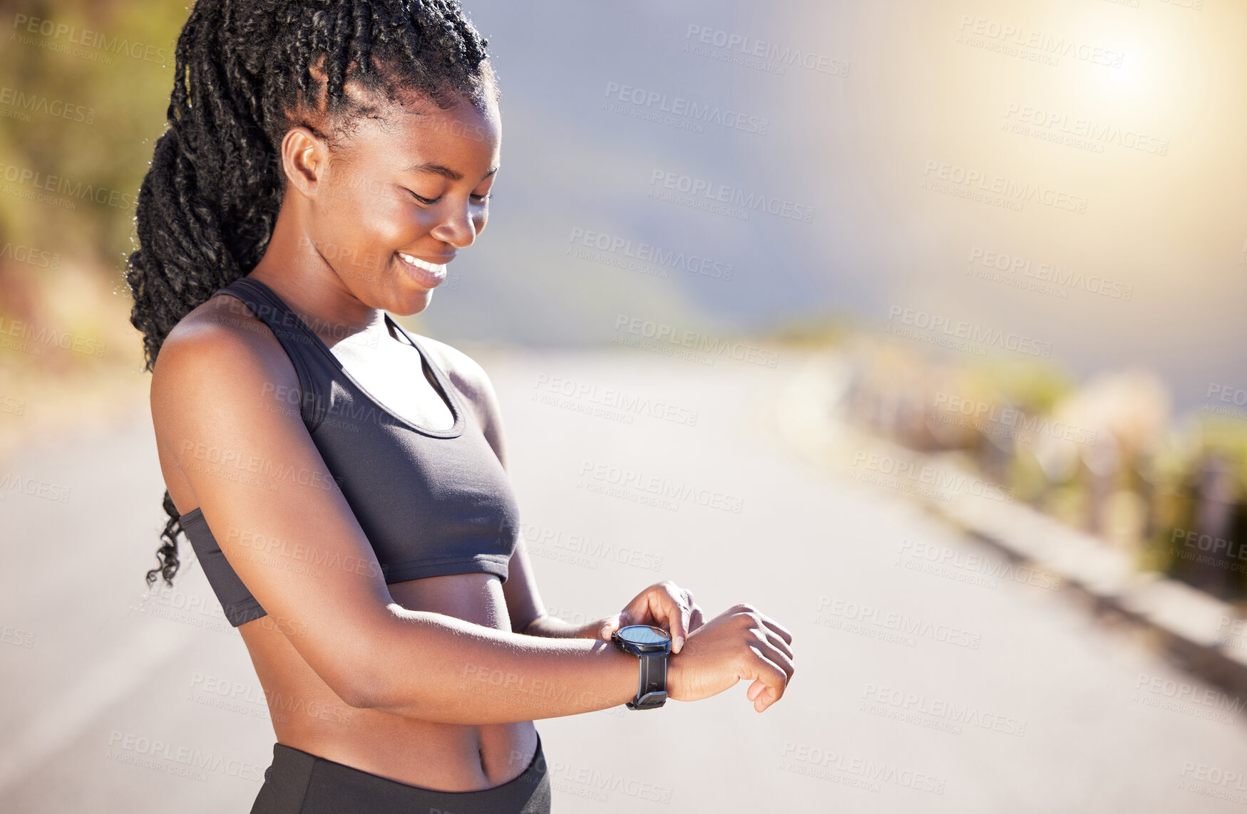 Buy stock photo One beautiful african american female athlete checking her smartwatch while exercising outdoors. A young athletic woman smiling while tracking her progress on a fitness watch during her workout