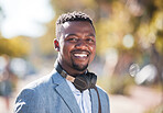 African American man wearing headphones while out in the city. Portrait of a happy handsome black male enjoying music on his daily commute to work. young businessman outside 