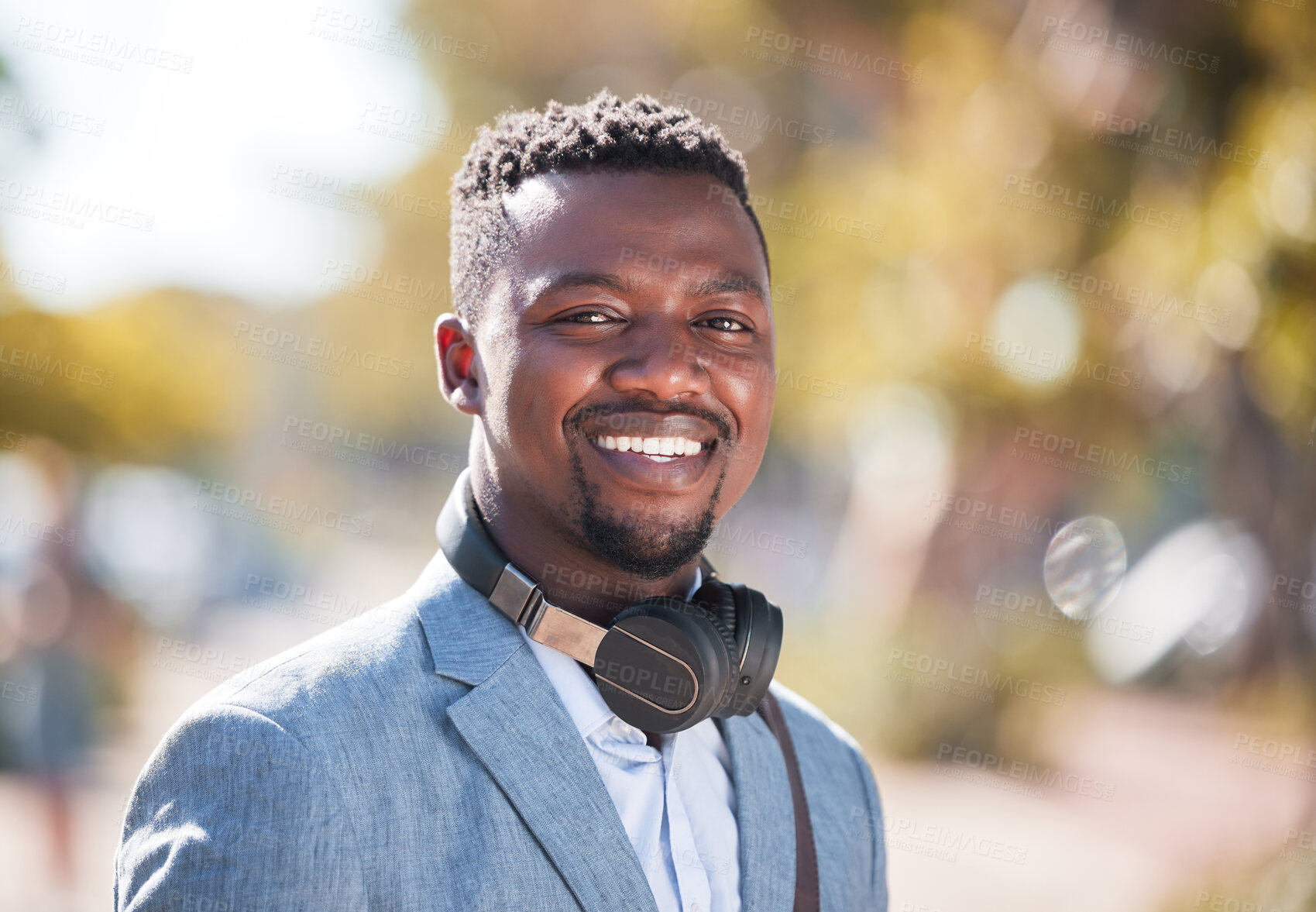 Buy stock photo African American man wearing headphones while out in the city. Portrait of a happy handsome black male enjoying music on his daily commute to work. young businessman outside