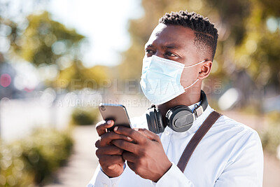 Buy stock photo Unrecognizable black man wearing a mask to protect himself from the corona virus pandemic while wearing earphones and texting on a cellphone. Businessman walking to a an interview using gps on a phone