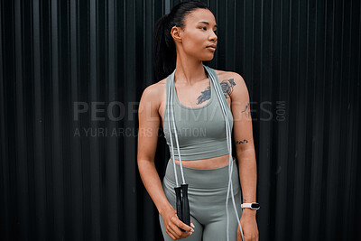 Buy stock photo Young mixed race hispanic female  wearing gymwear using a skipping rope while workout out outside in the city. Exercise is good for your health and wellbeing