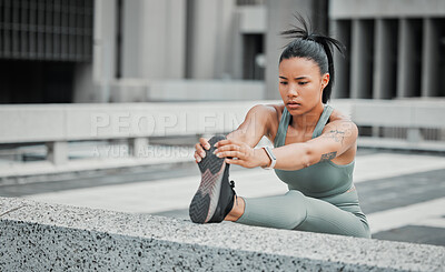 Young mixed race hispanic female athlete stretching her leg before a run outside in the city. Exercise is good for your health and wellbeing. Stretching is important to prevent injury