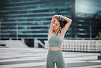 Mixed race female athlete stretching her arms by touching her back outside before exercising. Runner focused on her fitness and cardio health stretching her arm before starting her jog in the city