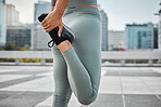 Close up of a female athlete stretching her legs while exercising outside in the city. Young woman warming up her muscles against a urban background. Stretching is most an important warmup in training