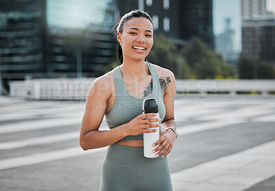 Buy stock photo Happy young mixed race fit female athlete smiling while taking a break holding water bottle and working out in the city. Exercise is good for your health and wellbeing