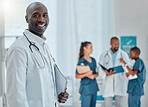 Portrait of a happy mature african american male doctor holding a folder working at a hospital with colleagues. Expert medical professional smiling ready for work at a clinic with coworkers