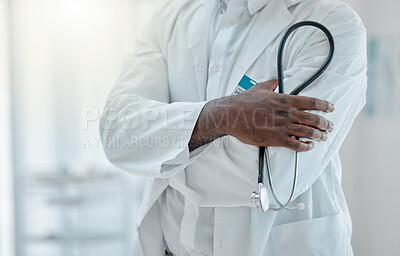 Buy stock photo Proud doctor standing with their arms crossed and holding a stethoscope while working at a hospital alone. One expert medical professional standing while at work at a clinic
