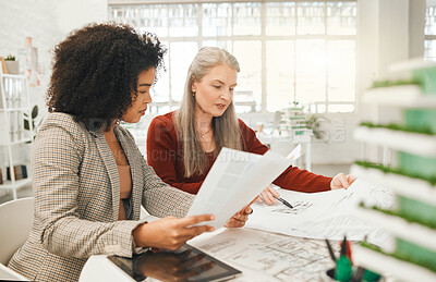 Buy stock photo Businesswoman reading a report with her colleague. Businesswomen in an agency collaborate to plan building project. Mature businesswoman working on a blueprint with a coworker. Team planning together