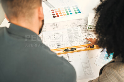 Businesspeople working on a blueprint from above. Two architects working on a building project together. Colleagues using a level during a meeting. Creative designers working on a building plan