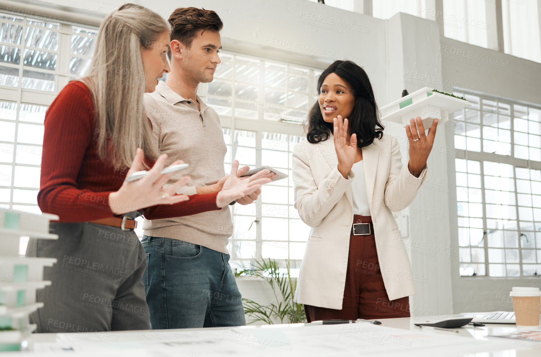 Buy stock photo African american businesswoman talking to colleagues. Team of architects planning a building model together. Colleagues collaborate on a 3D building model. Diverse businesspeople talking in a meeting