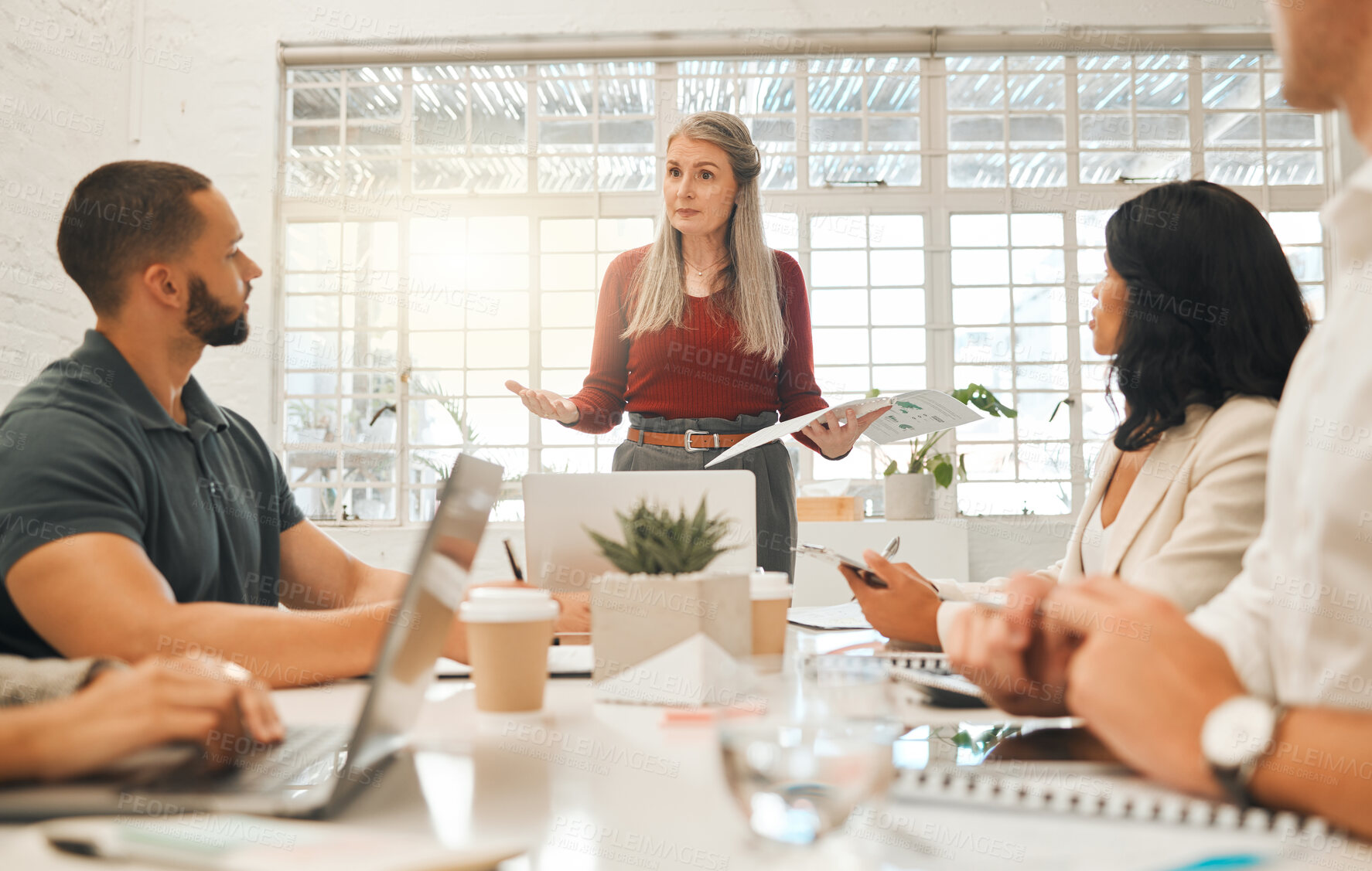 Buy stock photo Mature boss asking staff a question in a meeting. Businesswoman collaborating in a meeting. Senior architect using a report during a meeting.Diverse staff brainstorming together