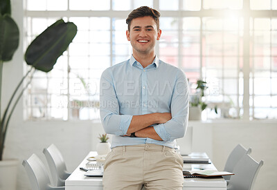 Buy stock photo Young caucasian businessman standing with his arms crossed in an office alone at work. Headshot of one happy male businessperson smiling while standing at work