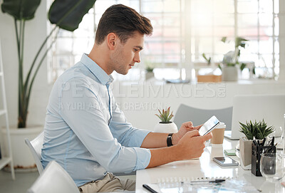 Buy stock photo Young caucasian businessman using a digital tablet at work. One serious male businessperson typing an email using a digital tablet while working in an office