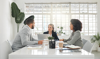 Buy stock photo Three businesspeople having a meeting together at a table at work. Business professionals talking and planning in an office. Mature caucasian boss talking to her employees