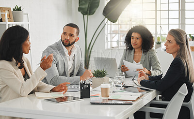Buy stock photo Group of four focused diverse businesspeople talking in a meeting together at work. Business professionals talking and planning in an office. Young african american businesswoman explaining an idea to colleagues at a table