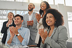 Group of businesspeople in a meeting together at work. Young cheerful mixed race businesswoman with a curly afro clapping with her colleagues while in a workshop. Business professionals clapping in support in an office