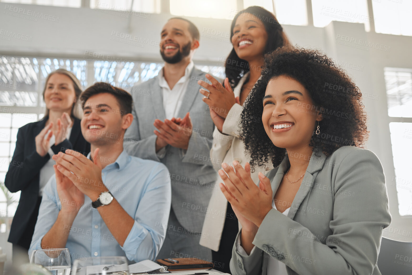 Buy stock photo Group of businesspeople in a meeting together at work. Young cheerful mixed race businesswoman with a curly afro clapping with her colleagues while in a workshop. Business professionals clapping in support in an office
