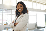 Young happy african american businesswoman standing with her arms crossed while in an office alone. One confident black female manager smiling and standing at work