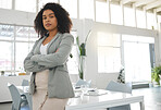Young mixed race businesswoman standing with her arms crossed while in an office alone. One confident hispanic female boss with a curly afro standing at work