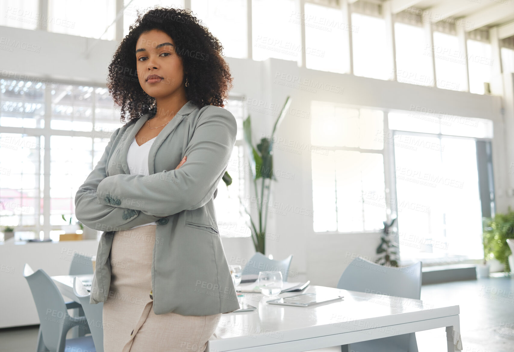 Buy stock photo Young mixed race businesswoman standing with her arms crossed while in an office alone. One confident hispanic female boss with a curly afro standing at work