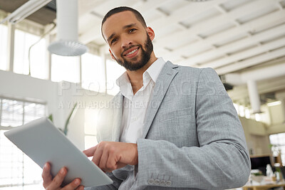 Buy stock photo Portrait of a young happy mixed race businessman working on a digital tablet in an office. One hispanic male boss smiling and holding a digital tablet at work