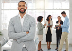 Young happy mixed race businessman standing with his arms crossed while in an office with colleagues. Hispanic male boss In a meeting with coworkers