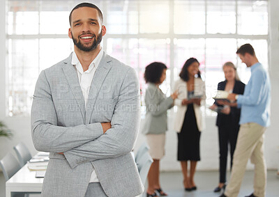 Buy stock photo Young happy mixed race businessman standing with his arms crossed while in an office with colleagues. Hispanic male boss In a meeting with coworkers