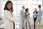 Young happy african american businesswoman standing with her arms crossed while in an office with colleagues. Black female boss In a meeting with coworkers