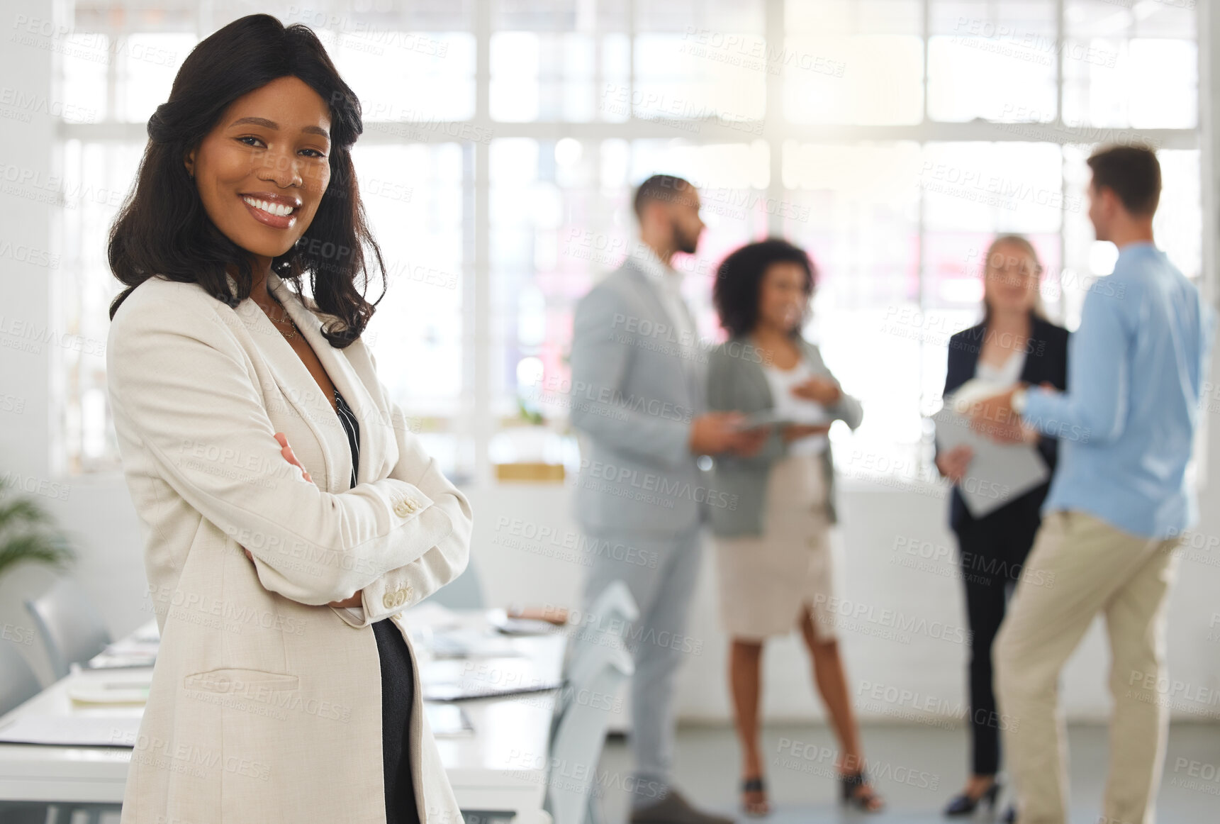 Buy stock photo Young happy african american businesswoman standing with her arms crossed while in an office with colleagues. Black female boss In a meeting with coworkers